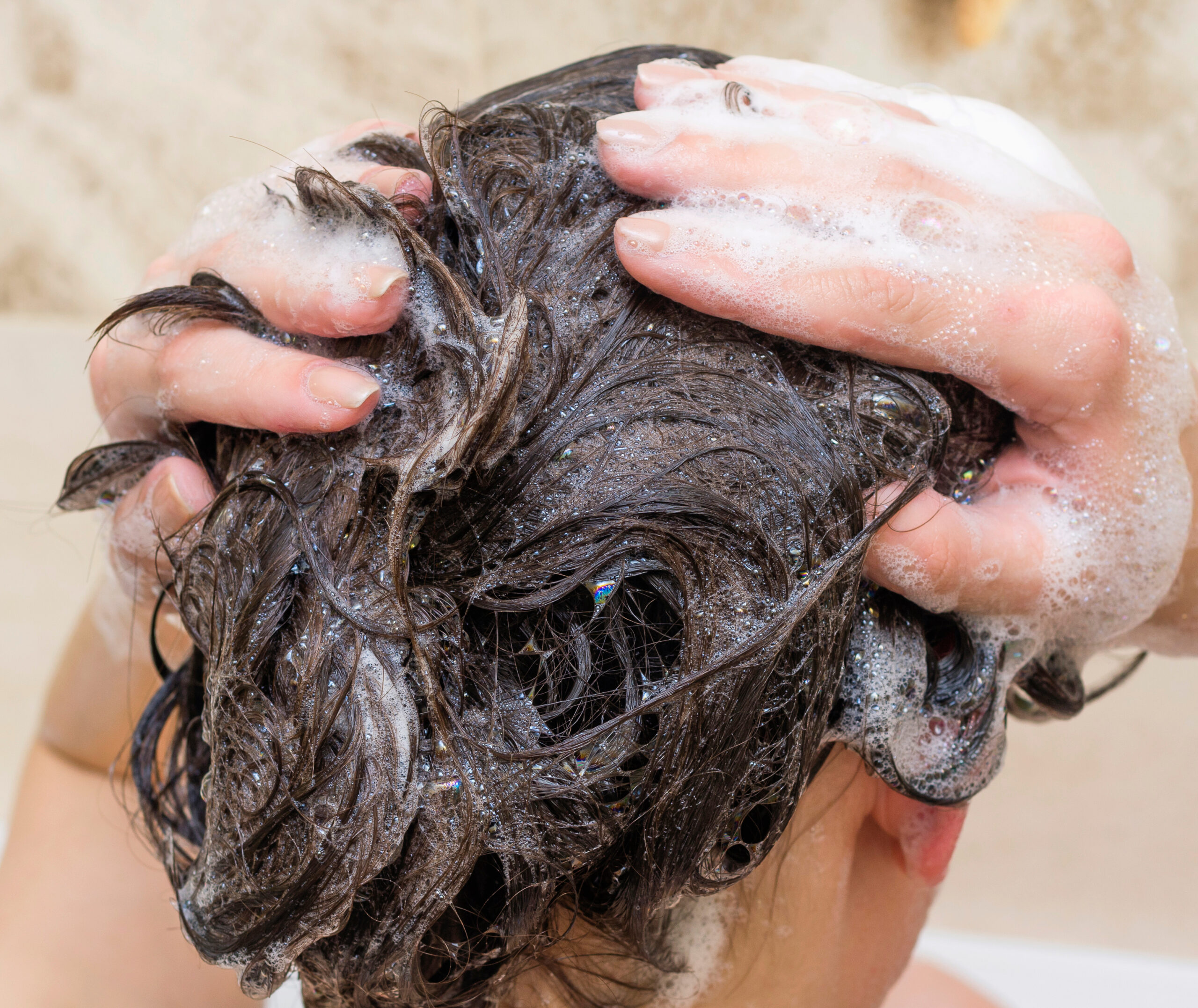 Kuvassa henkilö pesee hiuksiaan