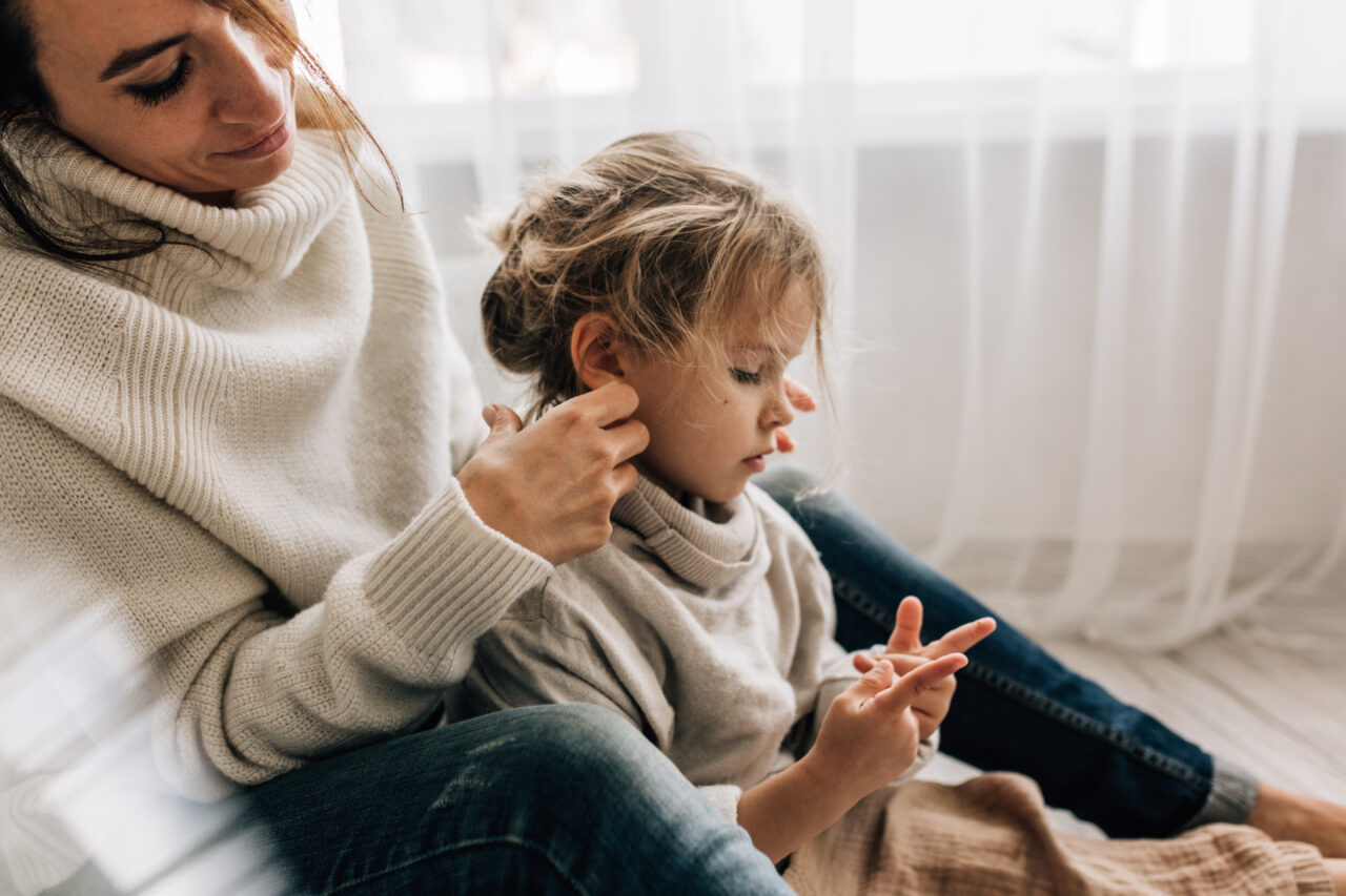 Kuvassa nainen laittaa lapsen hiuksia